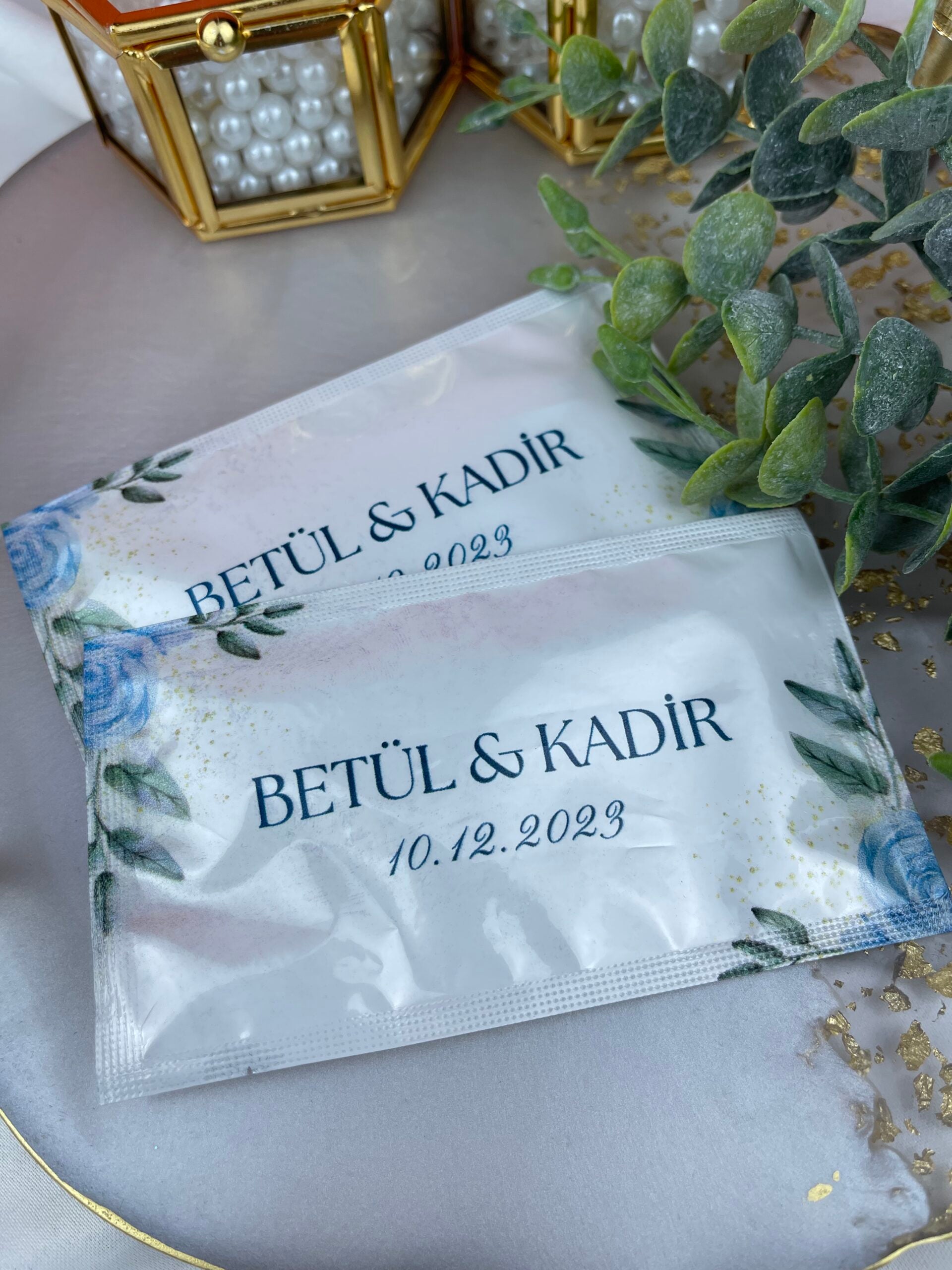 Mavi Gül ve Yaprak Desenli ıslak mendil yakın çekim — isim ve tarih baskısı detayı